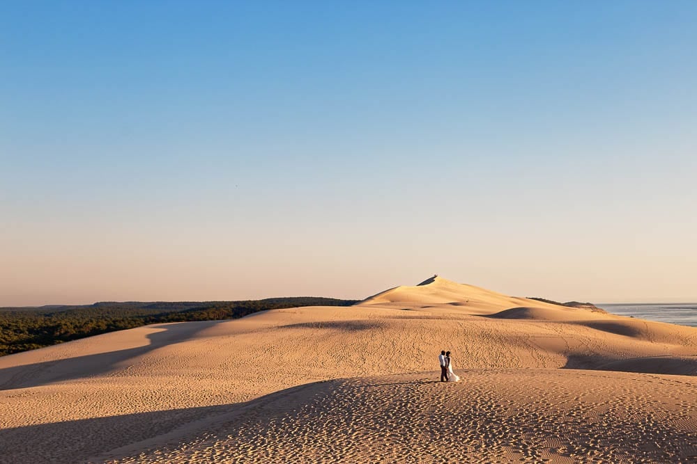 bride and groom in a landscape picture of desert dune during sunset time