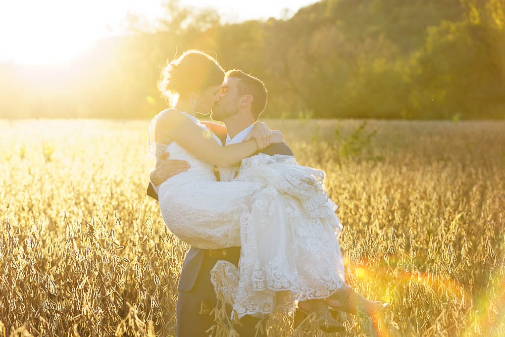 bride and groom kissing during sunset time in a field