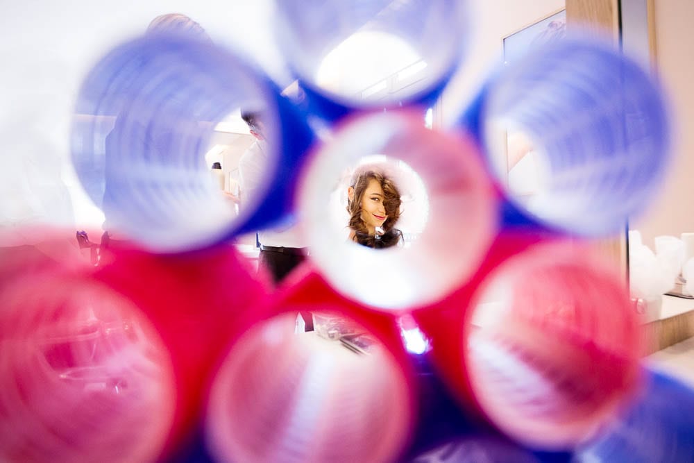 creative photograph of bride having hair done trough curlers at hair salon