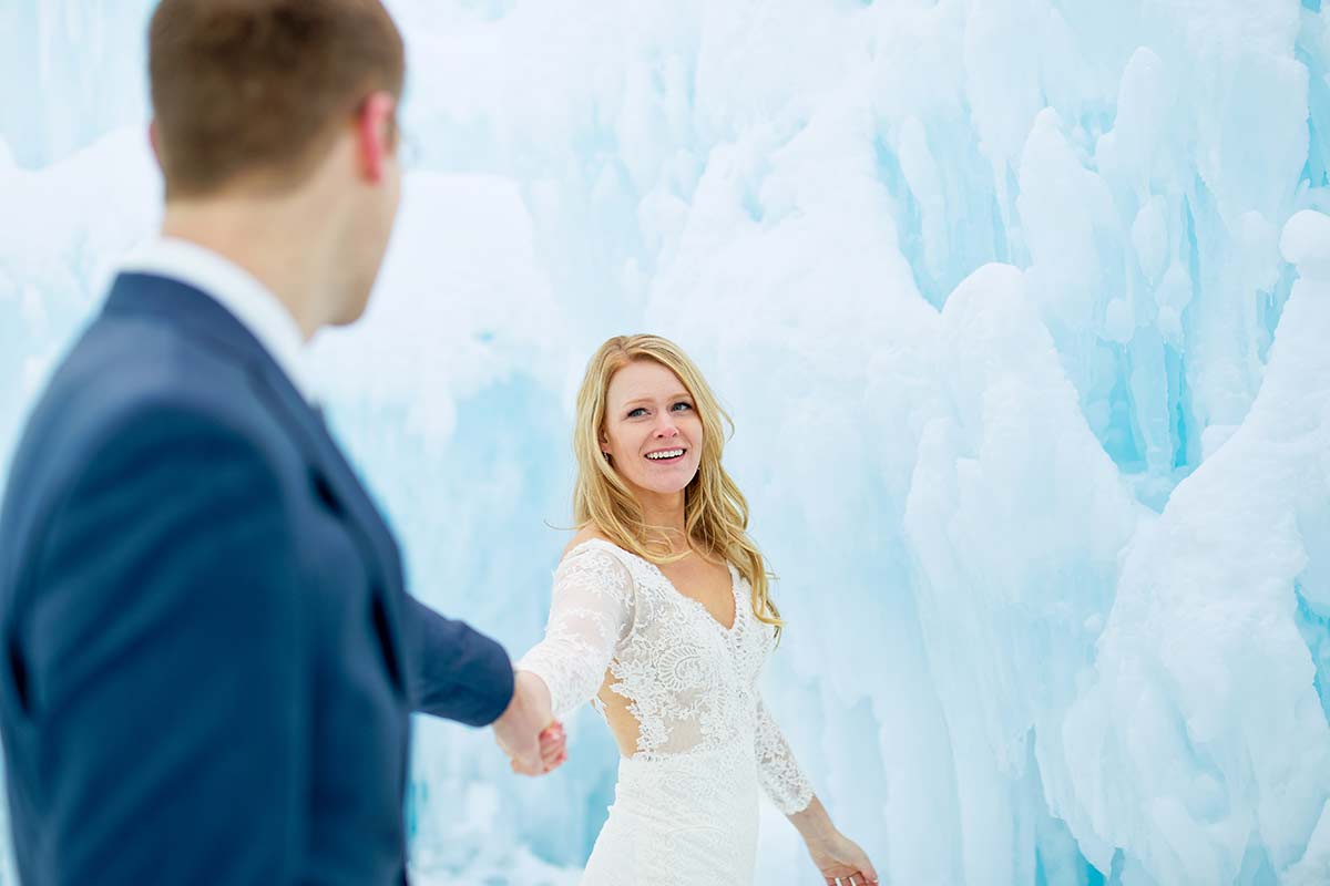 bride-pulling-the-groom-with-ice-backdrop