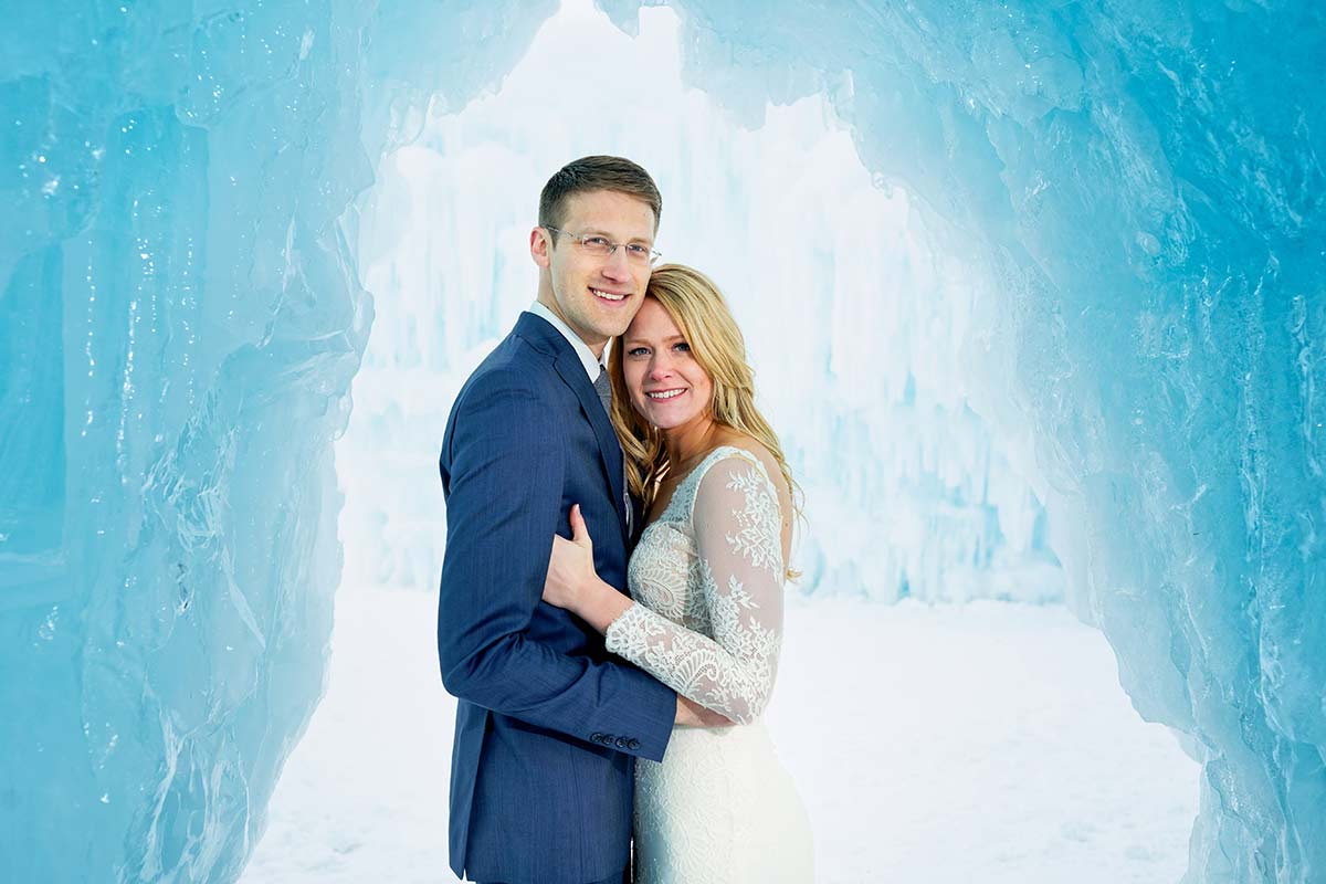 portrait-of-couple-with-blue-wall-of-ice-at-ice-castle-