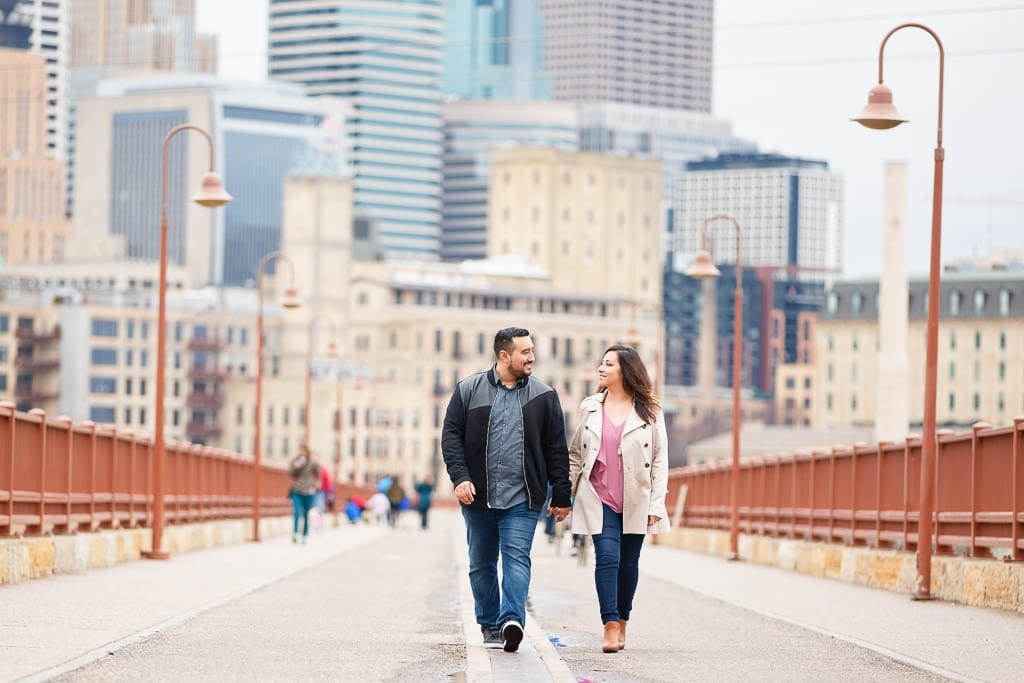 couple walking on stone arch bridge near nicollet anthony main minneaplis