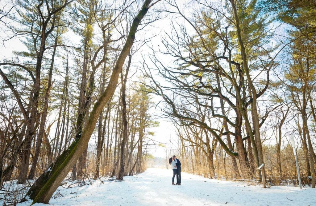 couple photographed kissing with naturalist forest as backdrop