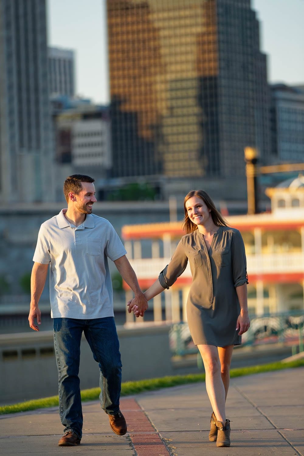 Happy couple during minnesota engagement Happy couple holding hands alongside the river