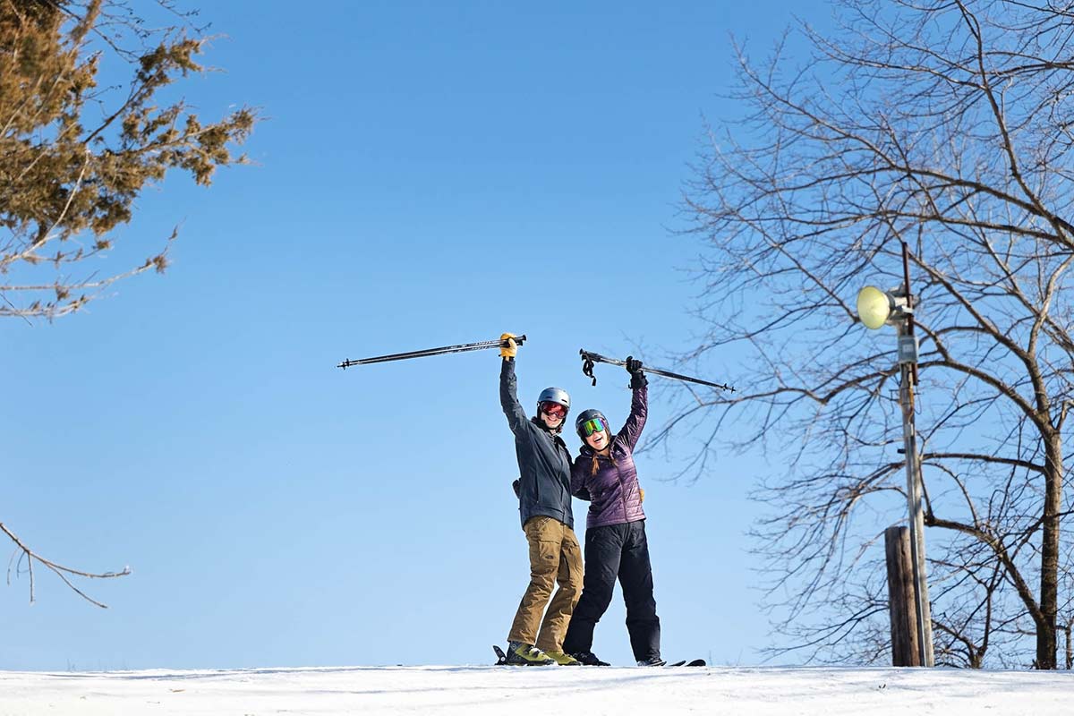 couple-at-the-top-of-the-hill-raising-arms-in-the-air-with-blue-sky