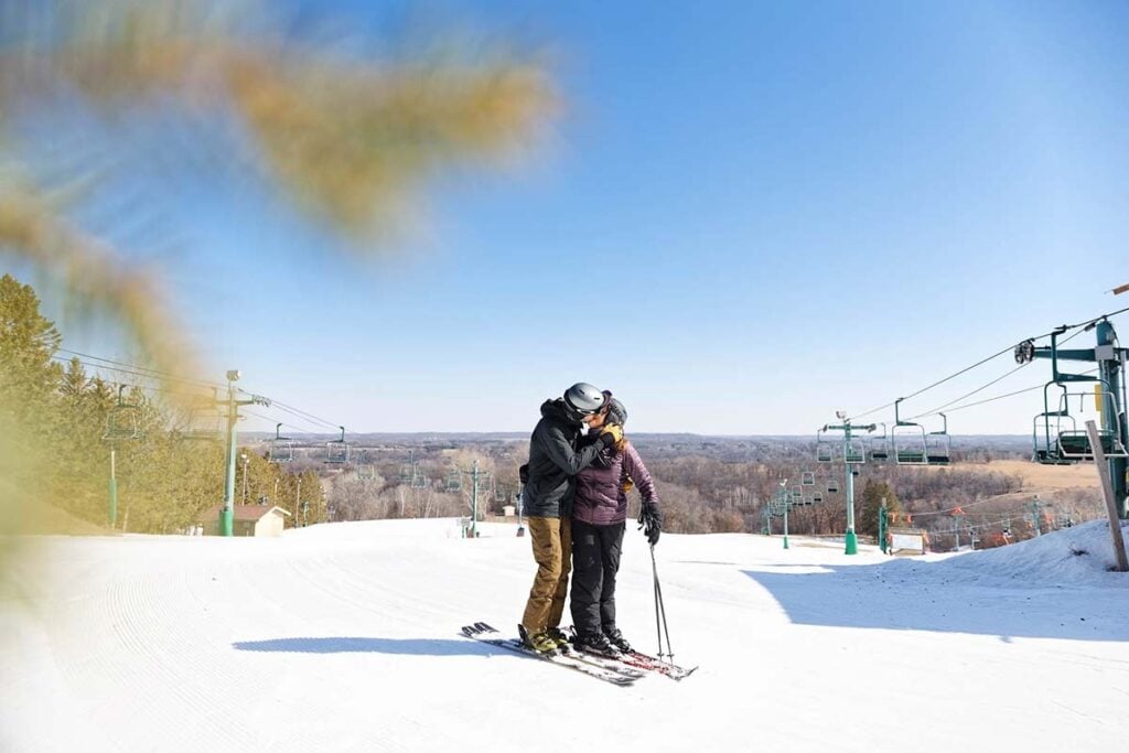 couple-in-ski-at-the-top-of-the-hill-kissing-view-on-minnesota