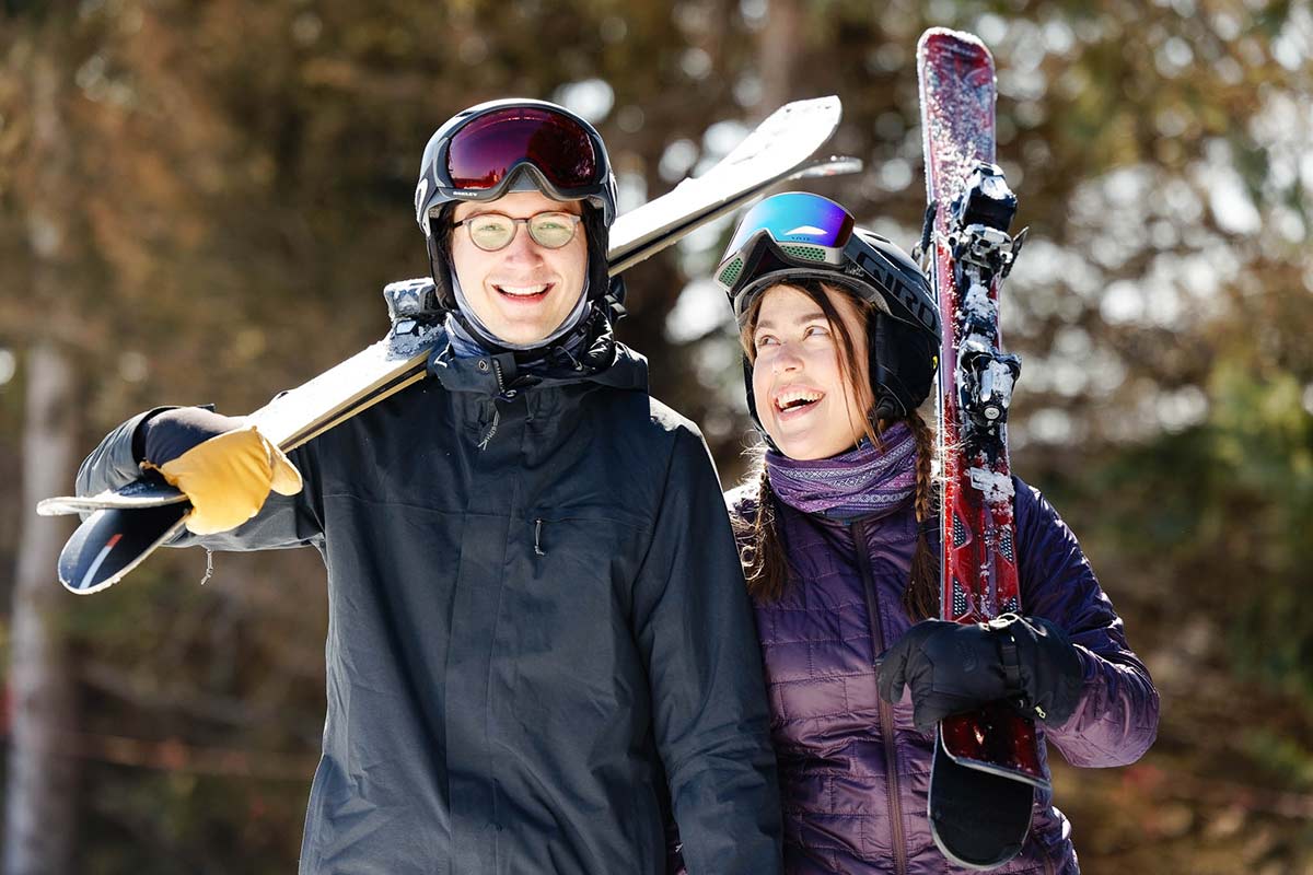 portrait-of-couple-walking-with-ski-gear-on-shoulder