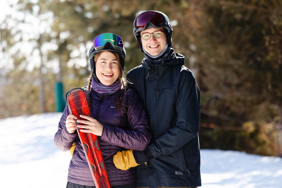 portrait-of-engaged-couple-with-ski-gear-looking-at-the-camera