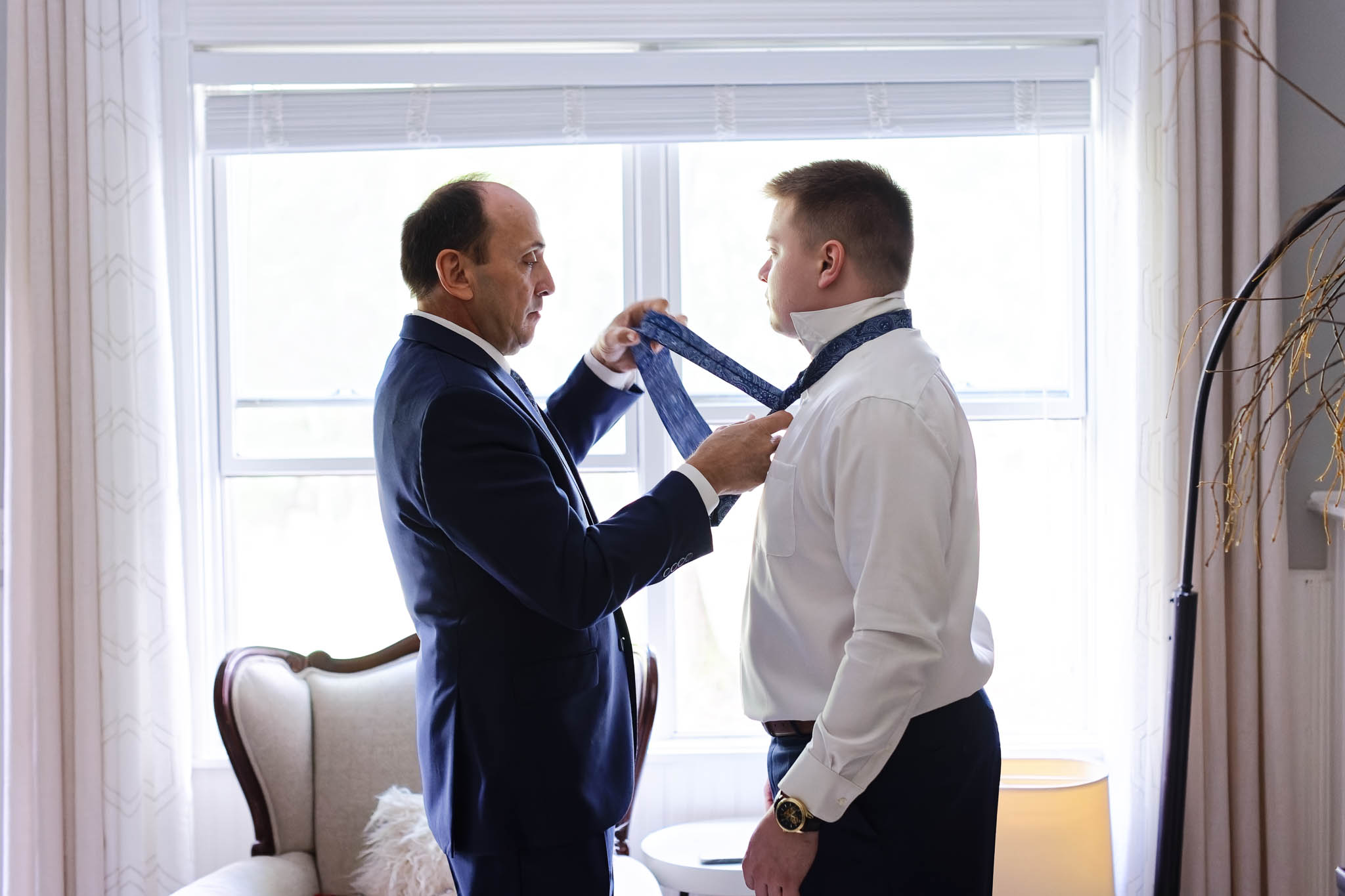 father helping groom with tie