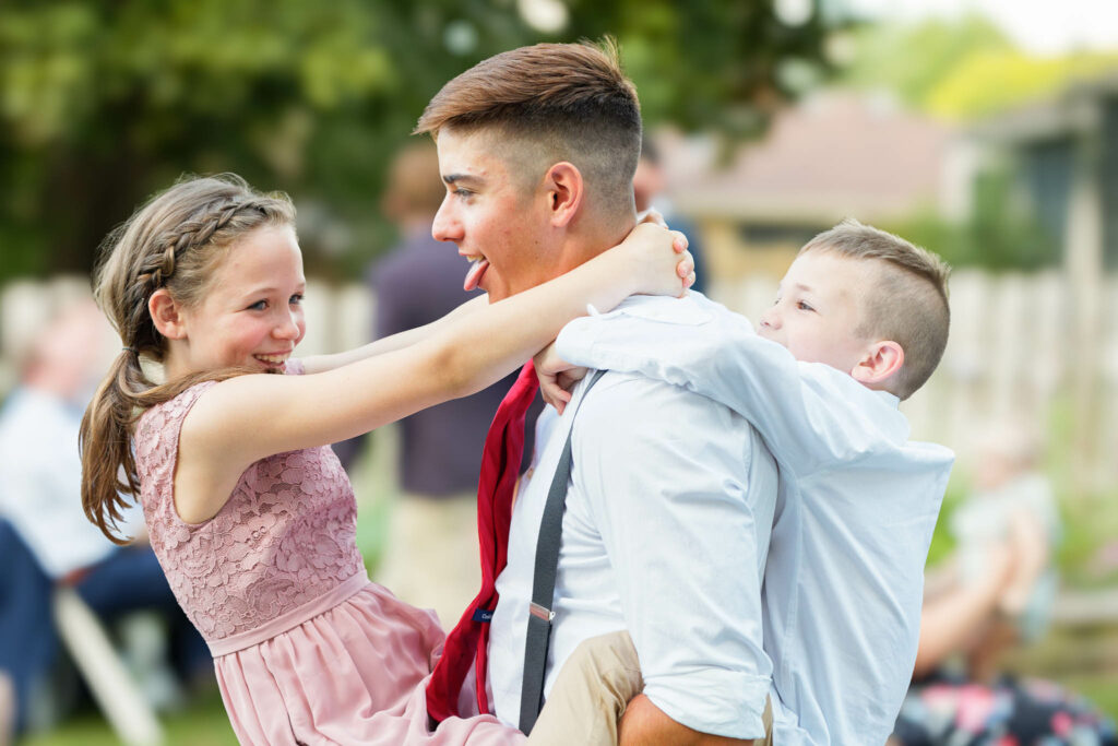 Three kids having fun during backyard wedding reception