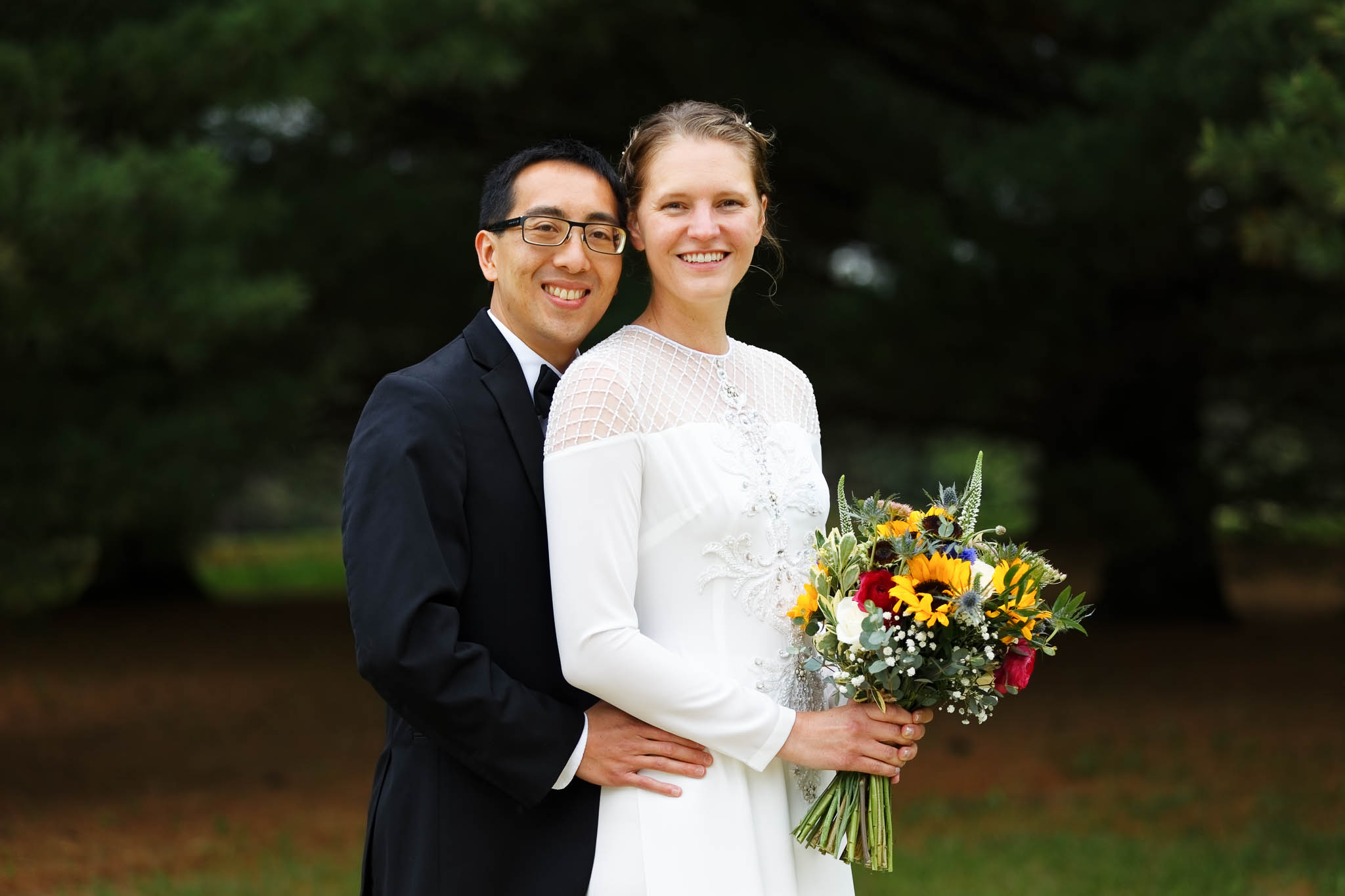 bride and groom with dark background with pine trees