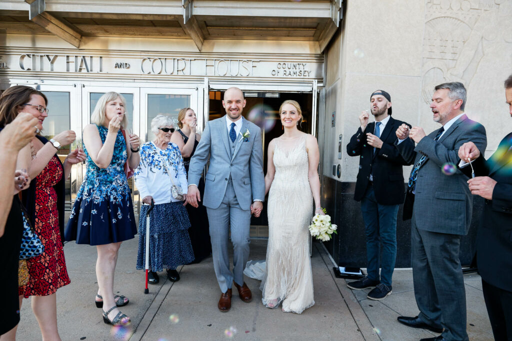 Bride and groom exiting the city all with guest blowing bubbles