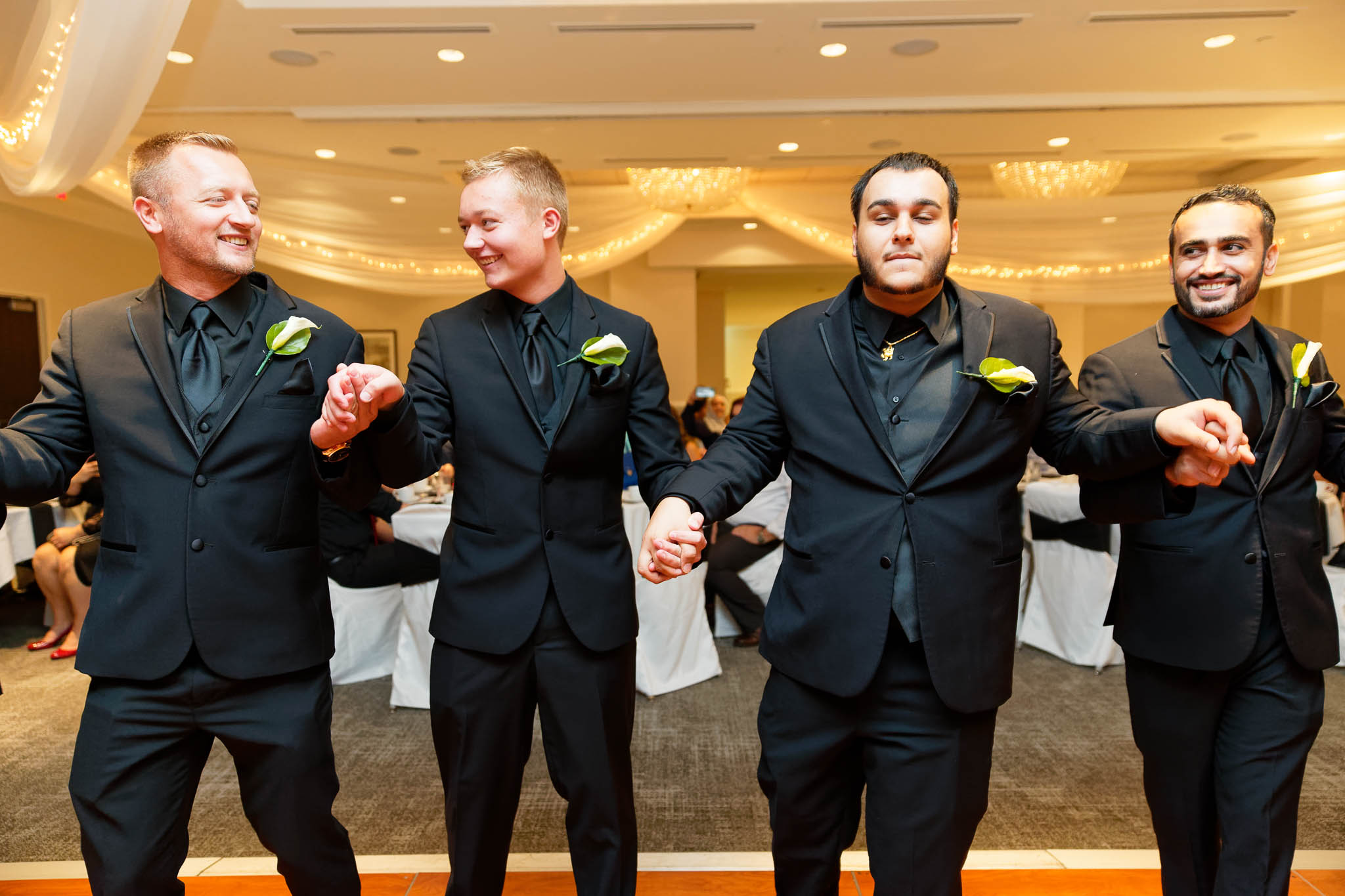 traditional dances groomsmen in black suite at hotel reception
