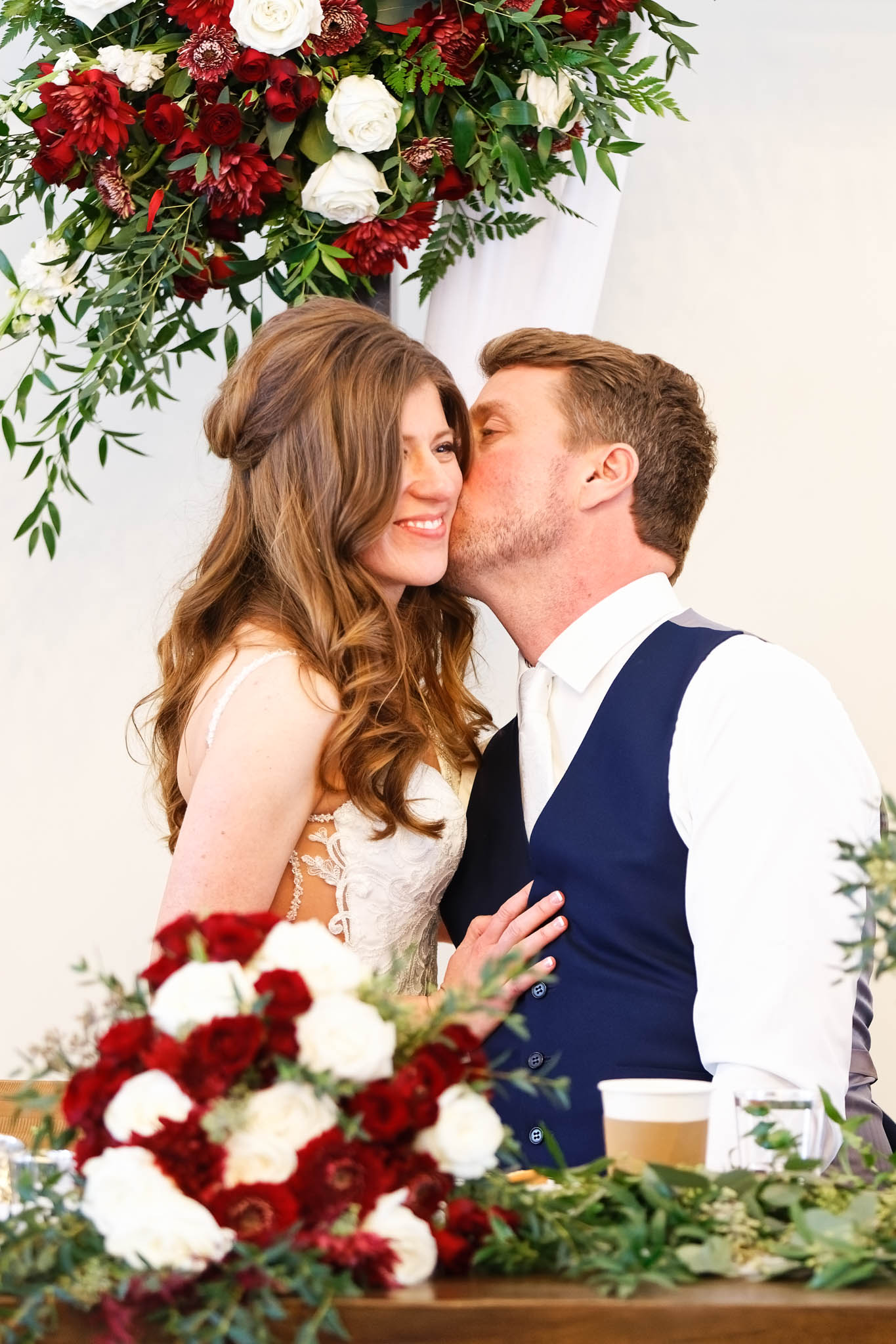 Bride and groom, kissing with Rose at reception table