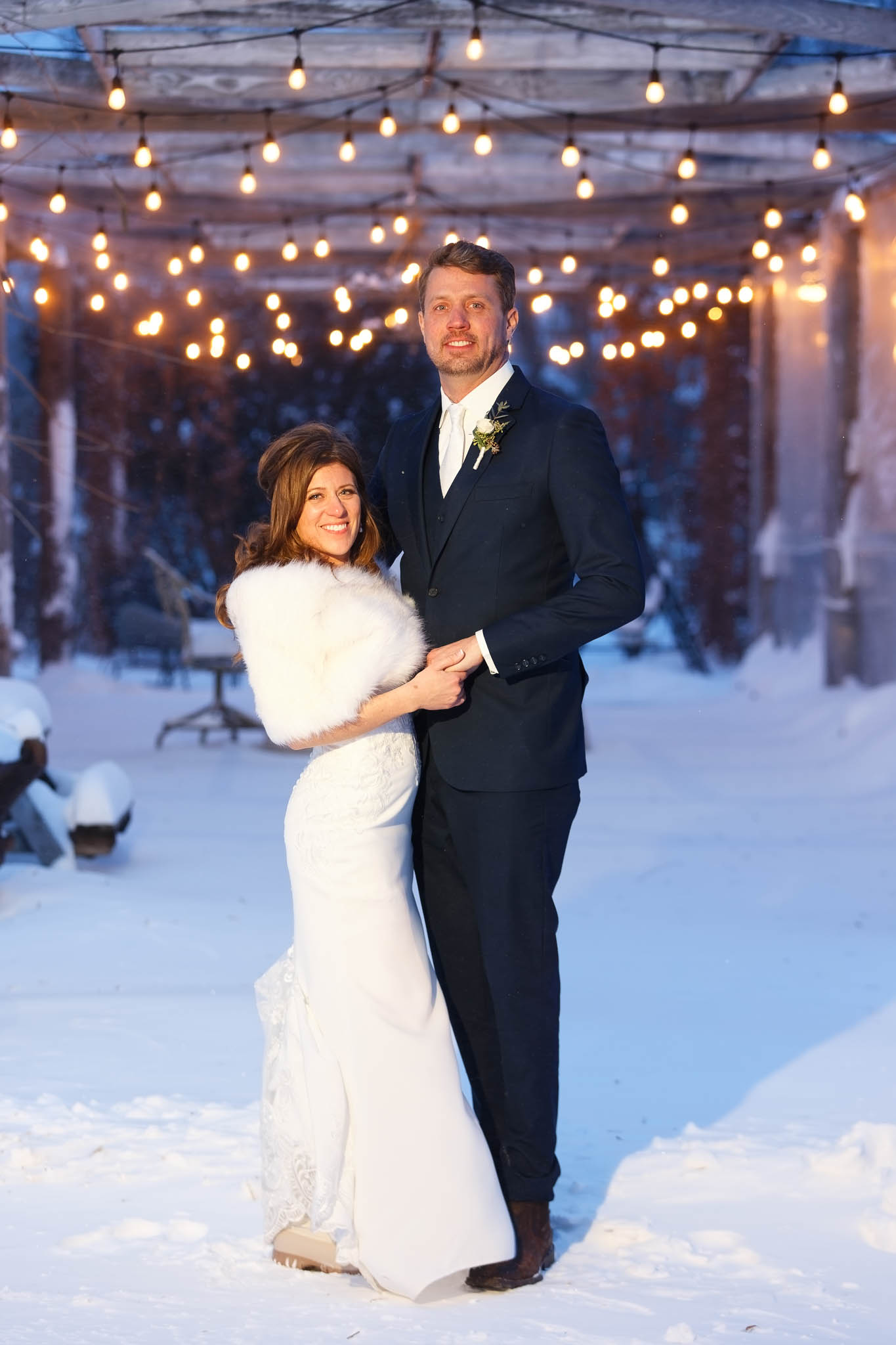 bride and groom winter photos with snow blue hour under pergolla with string light-2