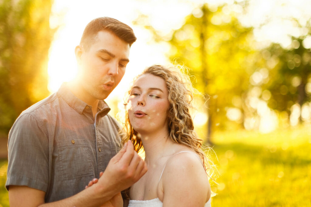 Couple blowing dandelion doing sunset