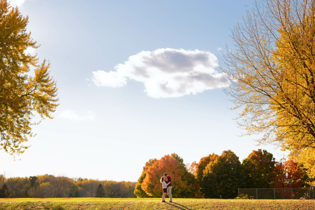 Happy couple playing and kissing with love during engagement session Rochester IBM park-5