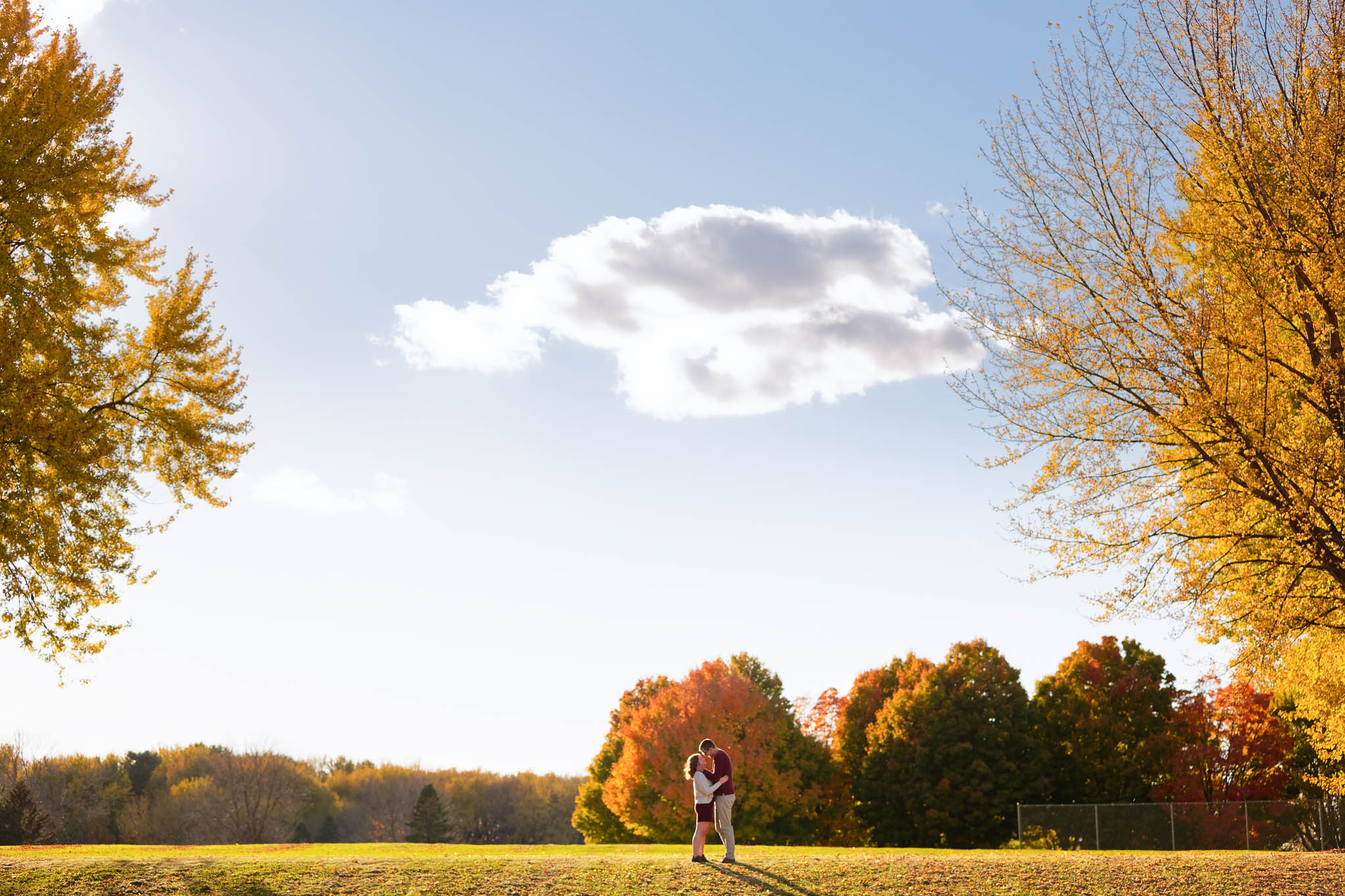 Happy couple playing and kissing with love during engagement session Rochester IBM park-5