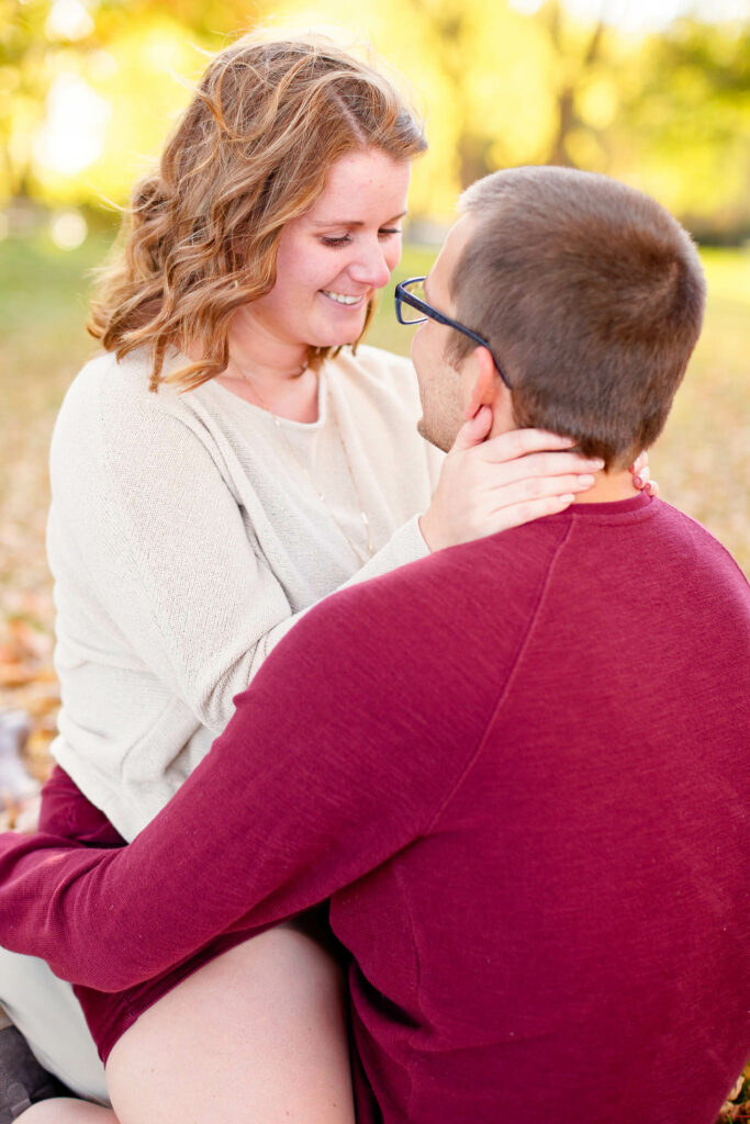 Happy couple playing and kissing with love during engagement session Rochester IBM park