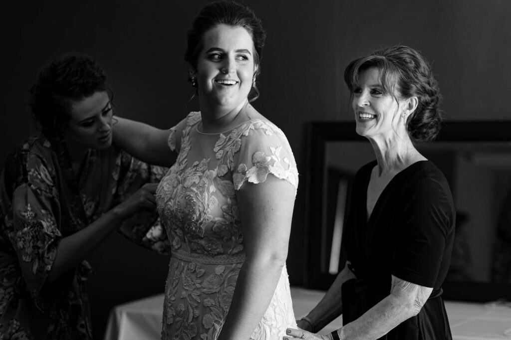 Black and white picture of the bride getting ready in a meeting room with her mother and sister