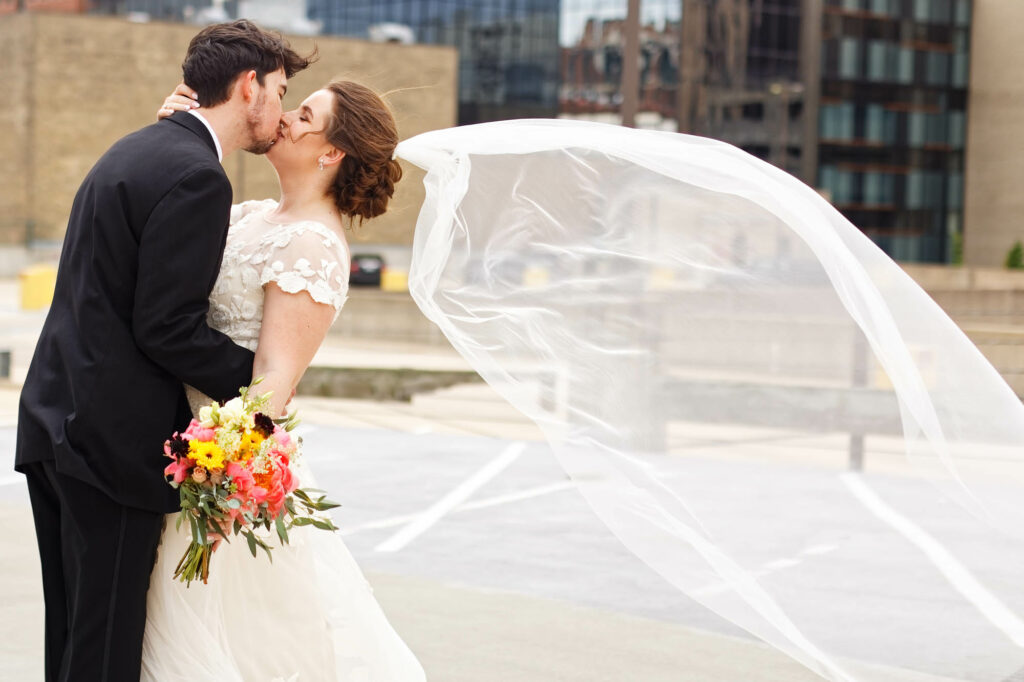 Bride and groom, picture, kissing on the rooftop with wind the veil is flying