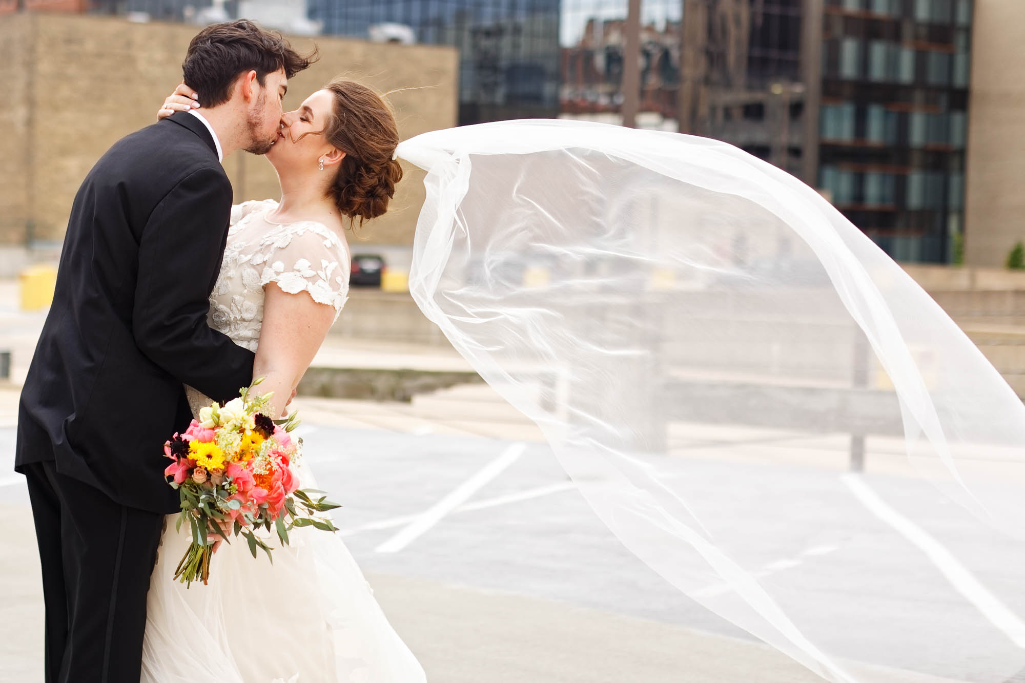 Bride and groom, picture, kissing on the rooftop with wind the veil is flying