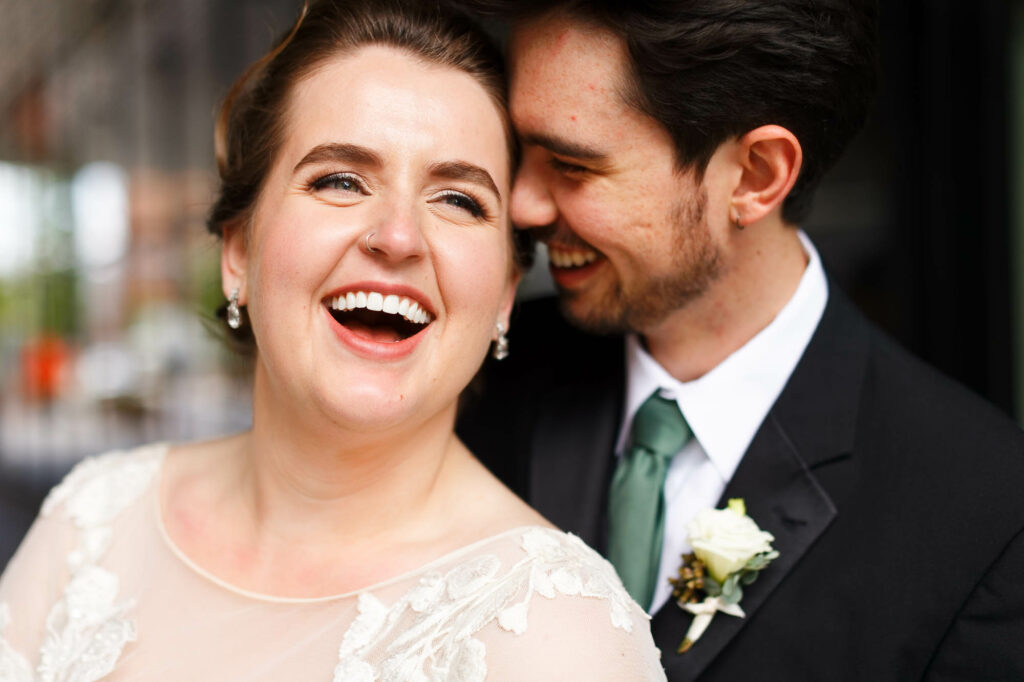 Bride laughing, while groom whisper