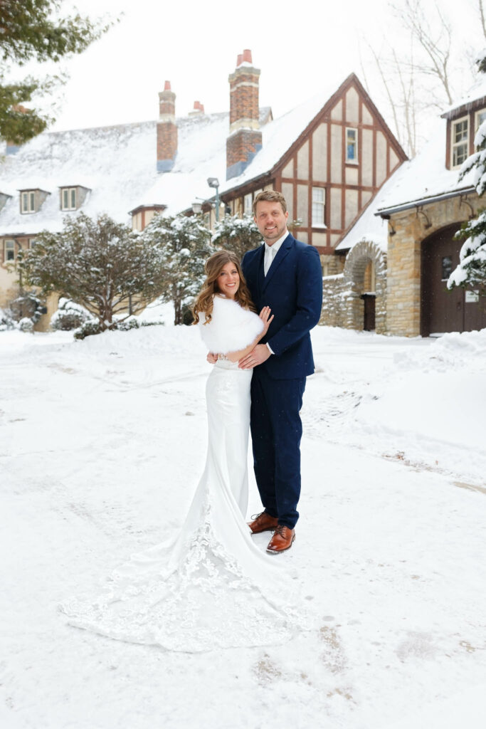 Bride and groom standing in front of plummer house cover with snow