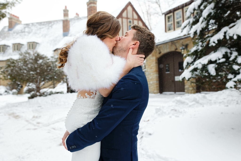 Couple kissing in front of plummer house with snow