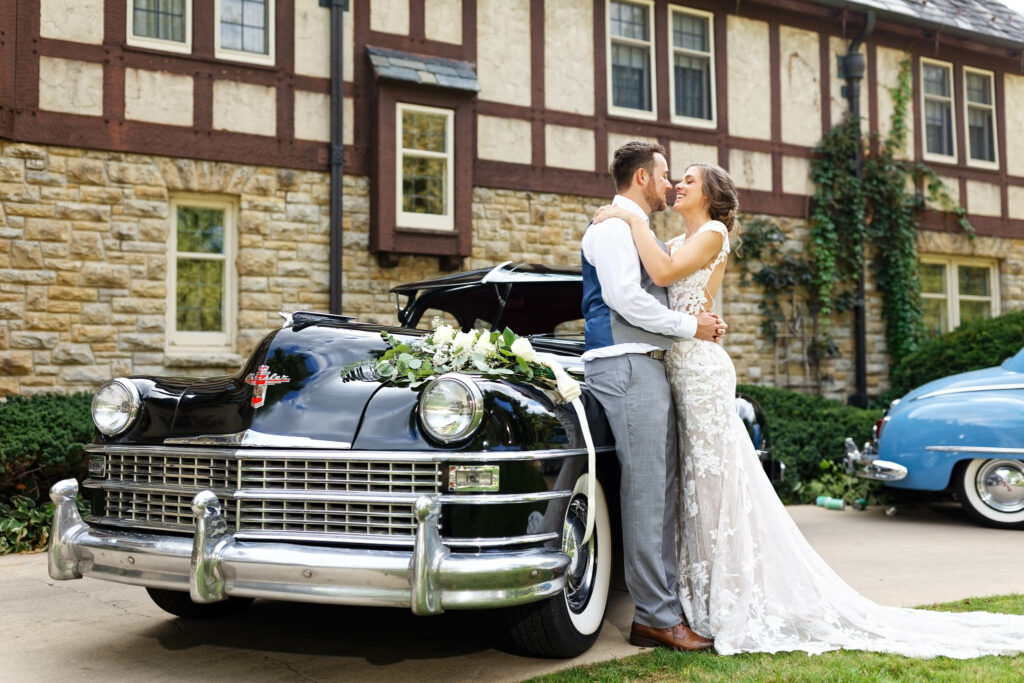 Couple with historic chrystler american car in front of Plummer House Tudor Mansion Rochester MN