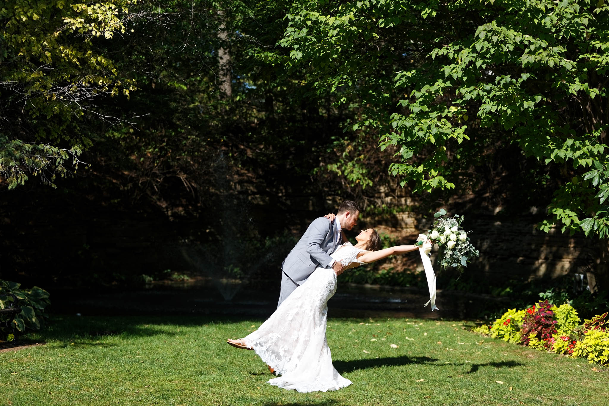 Groom dipping the bride in front of lower lawn fountain plummer house