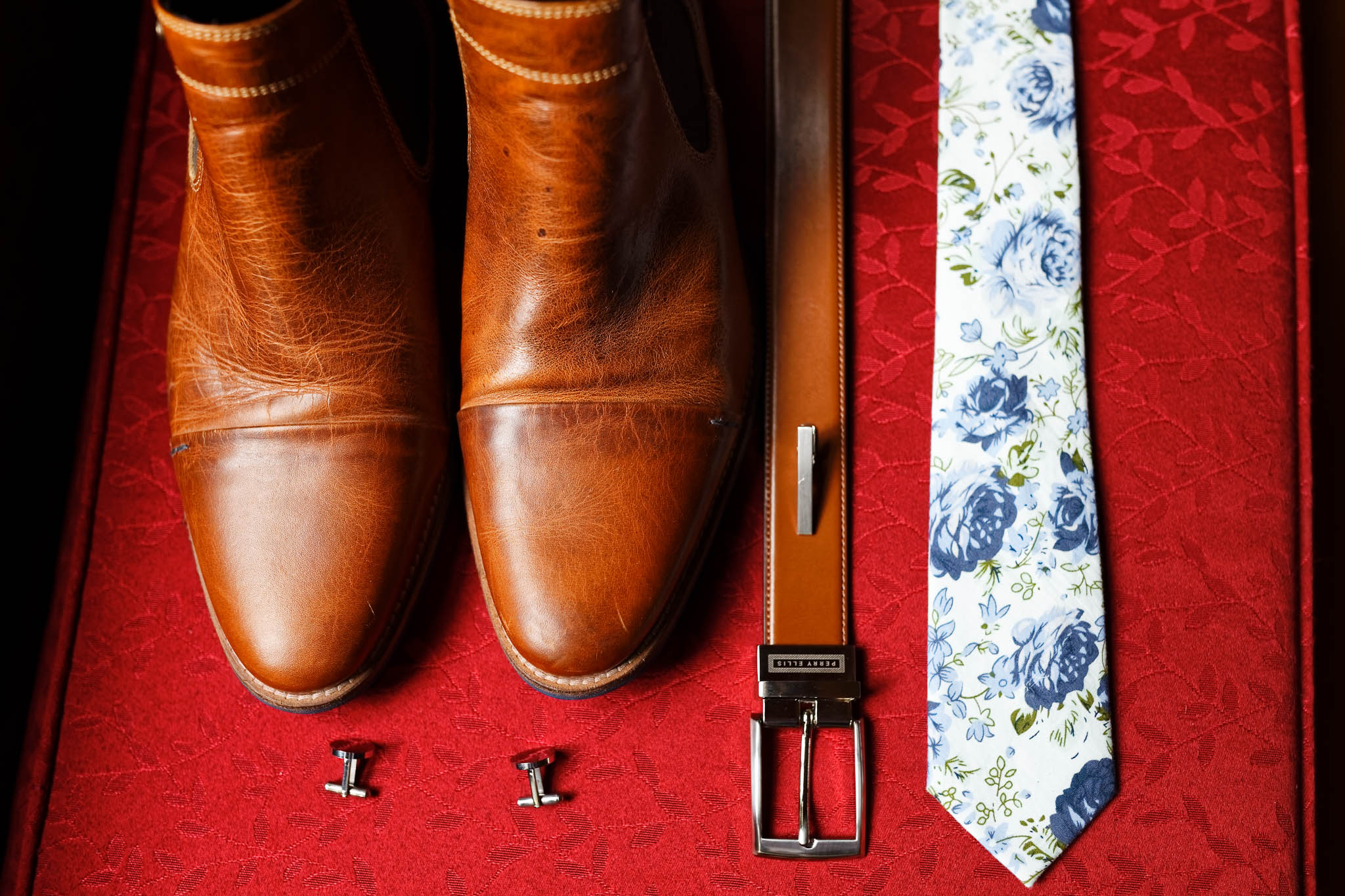 groom shoes tie cufflinks on red cushion material