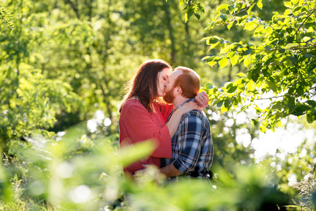 Couple kissing between three leaves and water lake in background