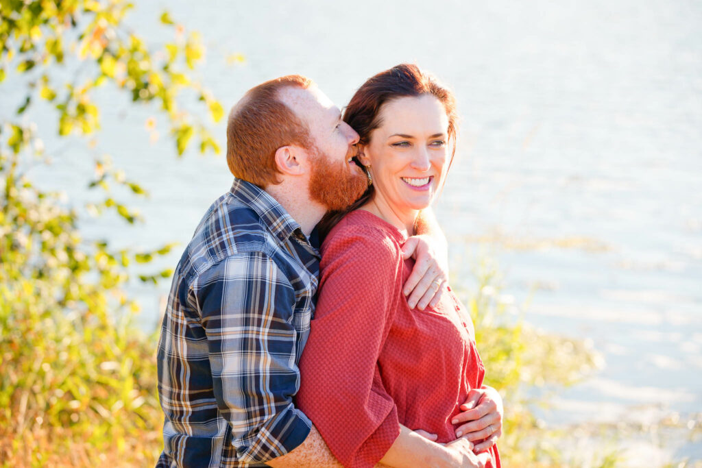 Couple whispering in front of Willow Creek Resevoir Park Rochester