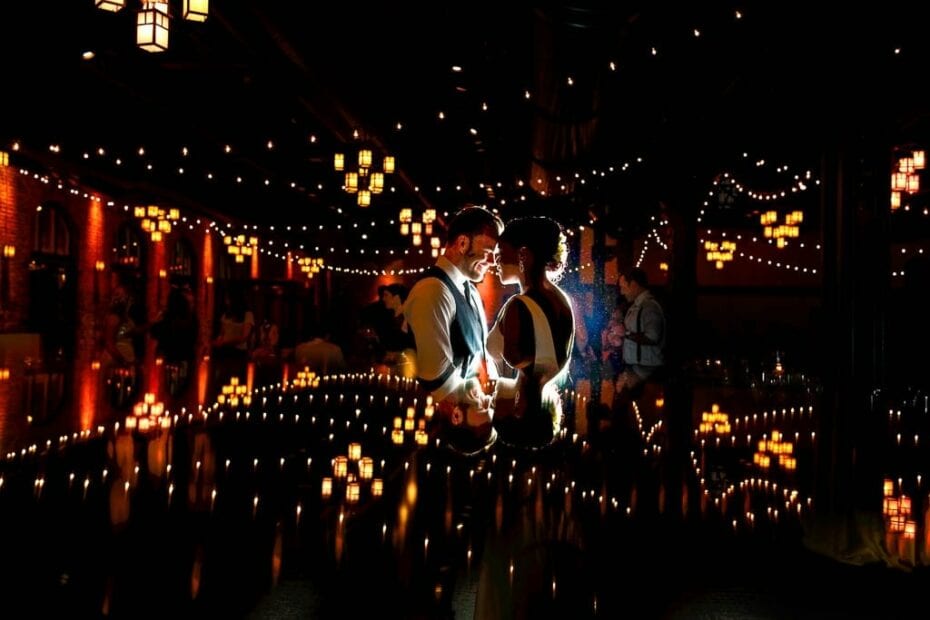 Couple hugging in post industrial backdrop and sting light at Nicollet Island pavillon