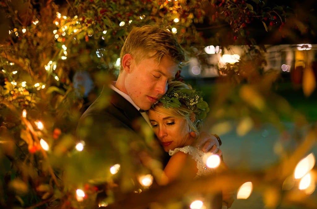 bride and groom hugging with fairy lights