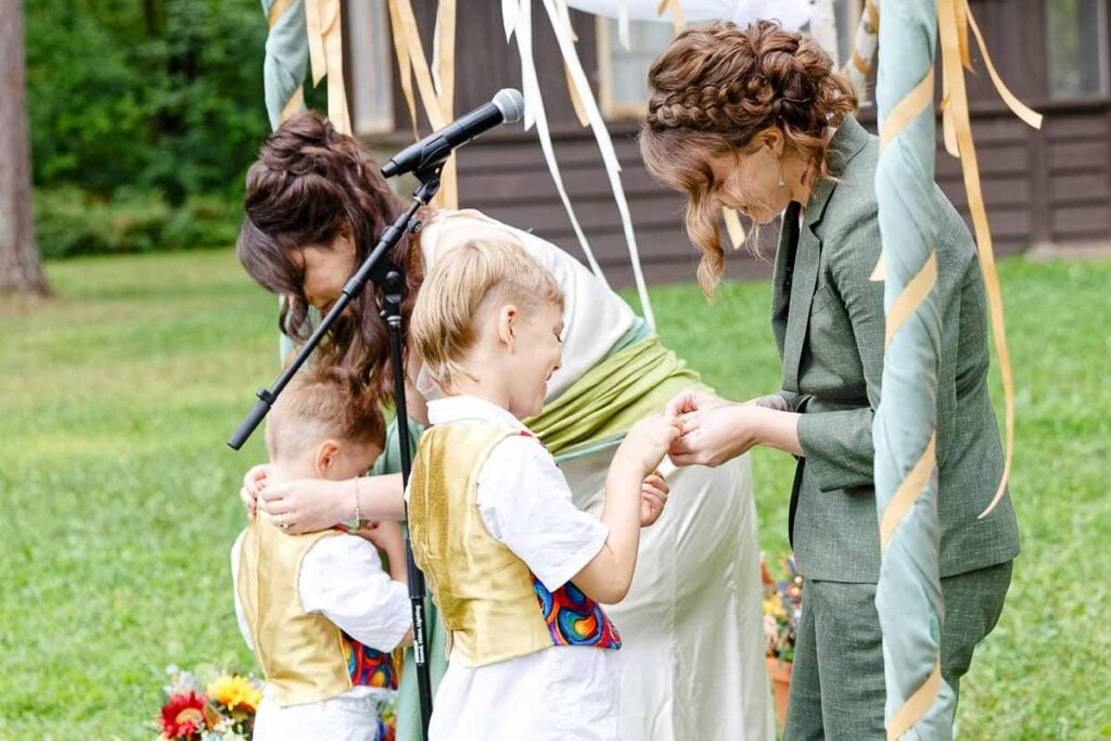 emotional moment during outdoor wedding ceremony, child receiving medallion from bride, candid documentary photography minnesota