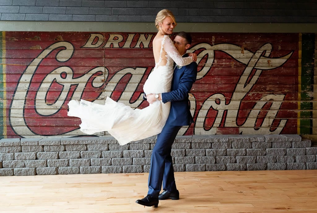 Bride and groom dancing in front old Coca cola wall