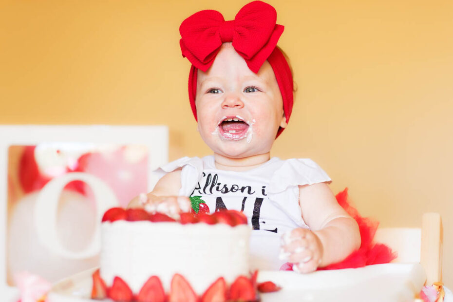 toddler with cake cream all over the face laughing
