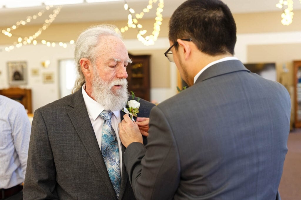 The groom pinning the boutonniere on his father