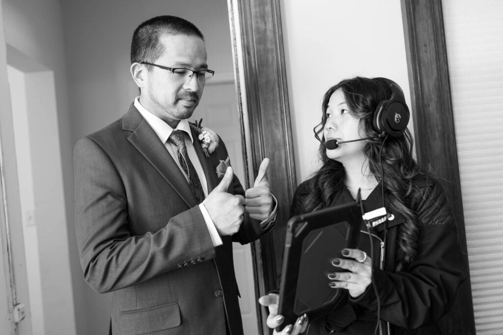 The groom giving two thumbs up while chatting with someone on an iPad held by his sister