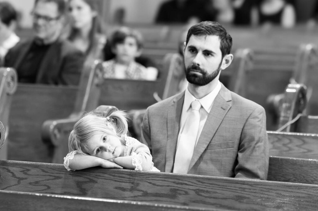 A little girl bored during the wedding ceremony, resting her head on the church pew