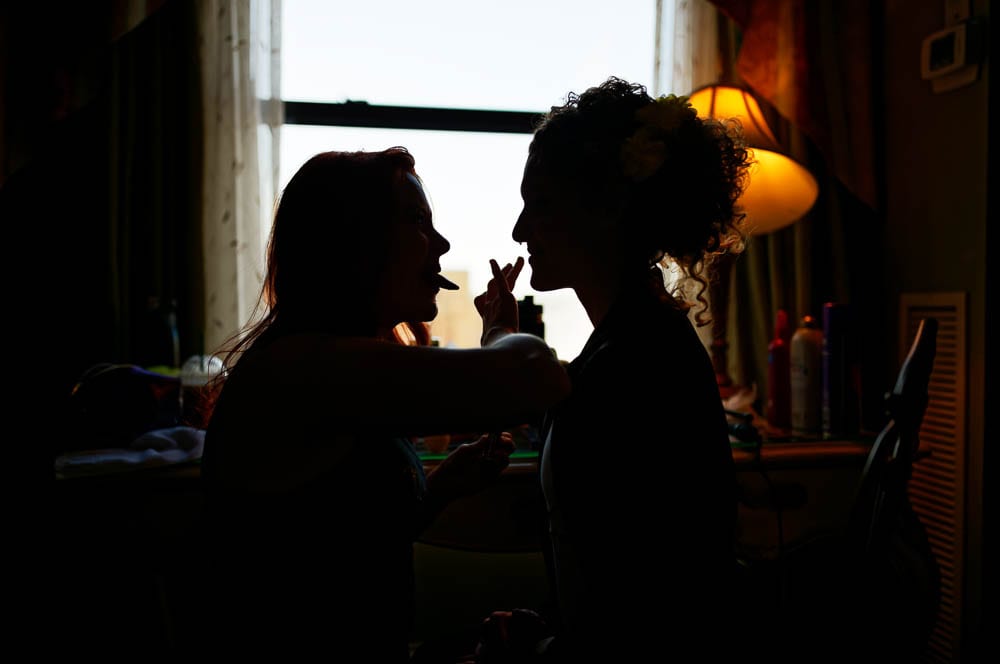 Silhouette of bride and makeup artiste having fun