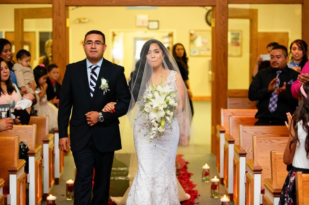 emotional bride walking down church aisle with her father