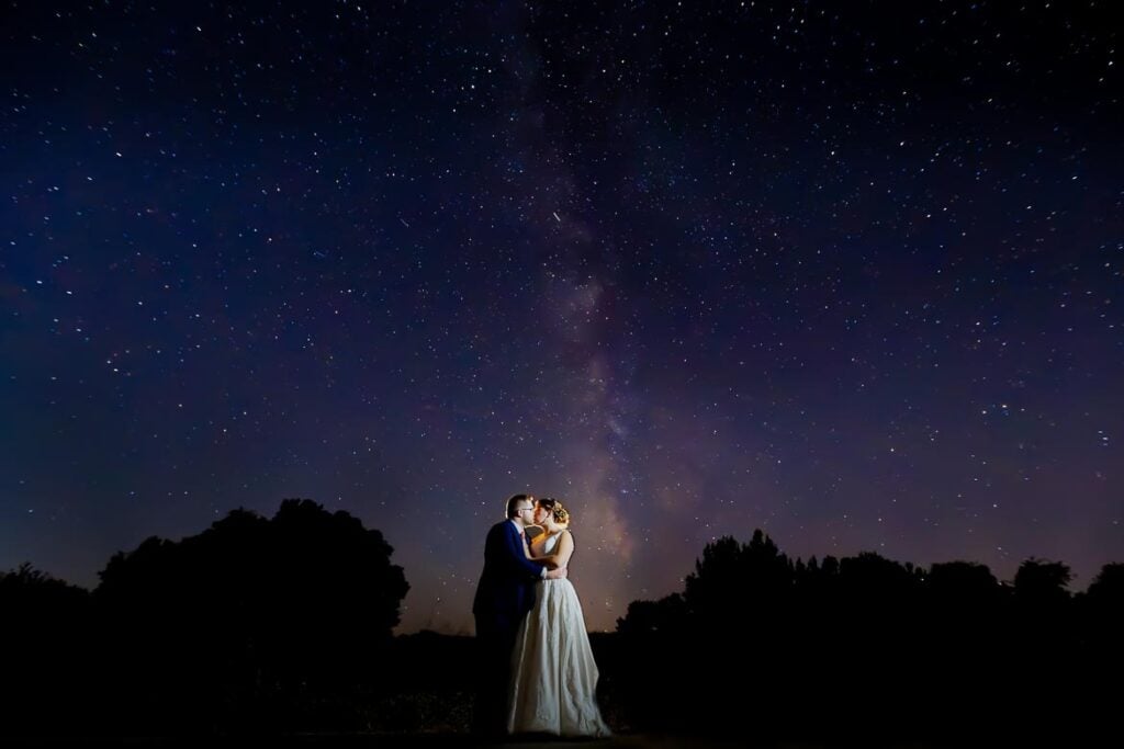 bride and groom kissing under milkyway