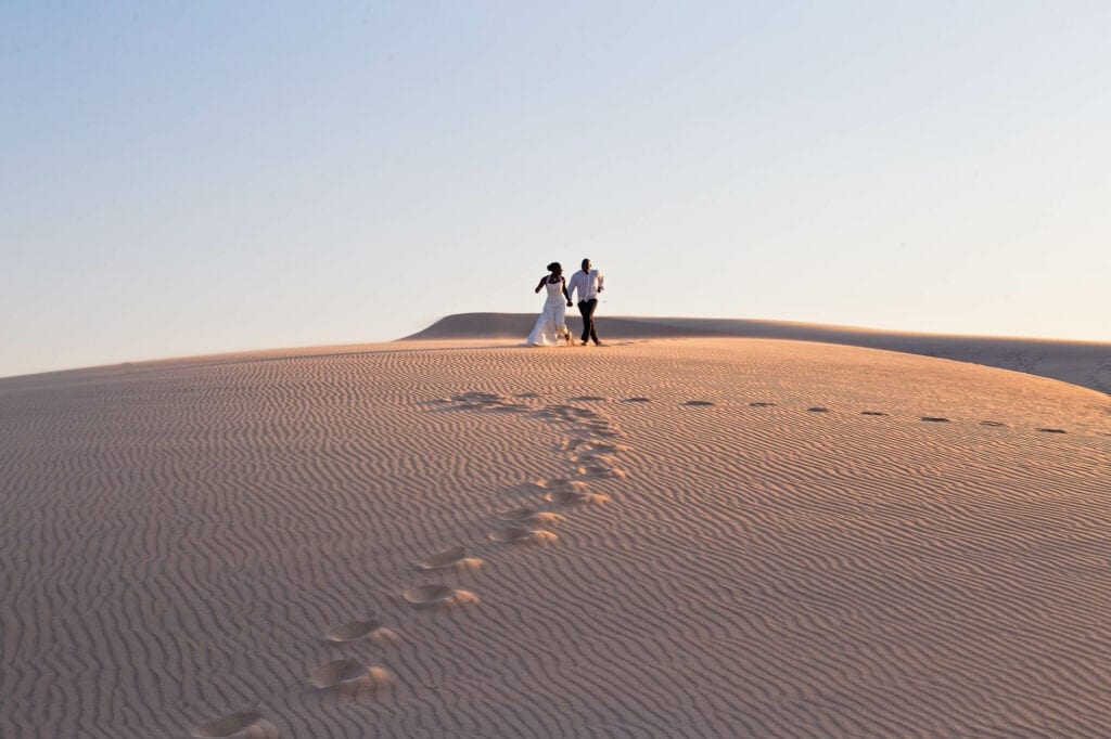 bride and groom runing in the desert