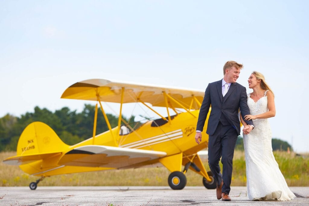 photo of a couple on a airport with yellow plane