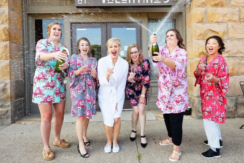 bride and bridesmaid open champagne