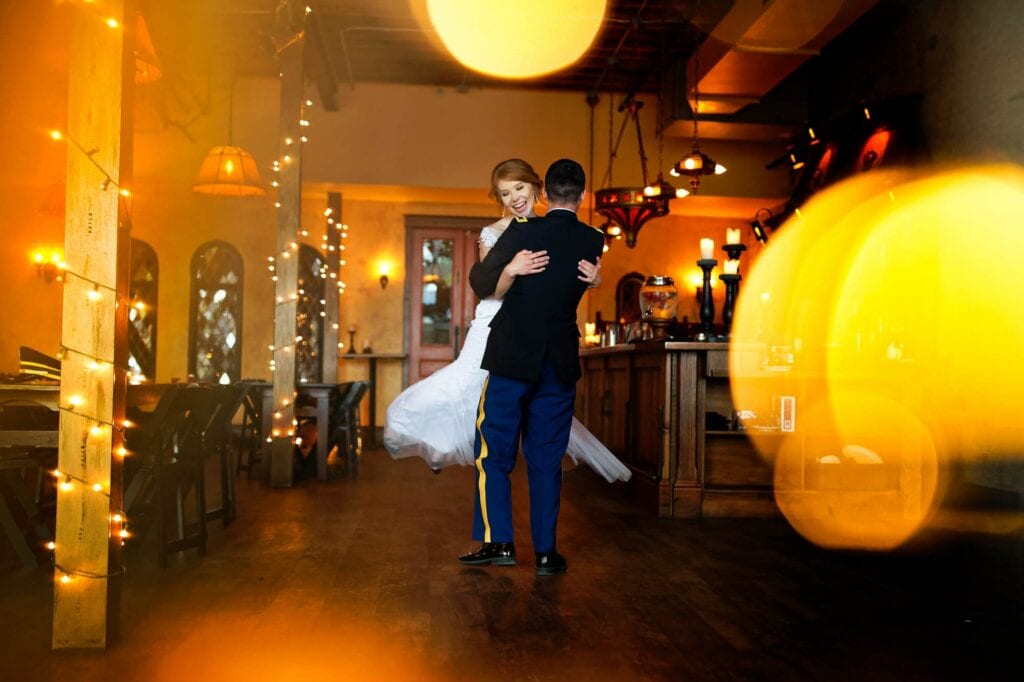 bride and groom dancing with lights in warm wood venue