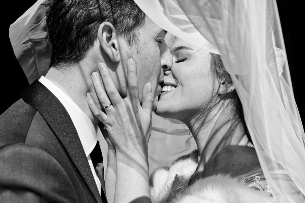 black and white close up of bridal kiss with veil